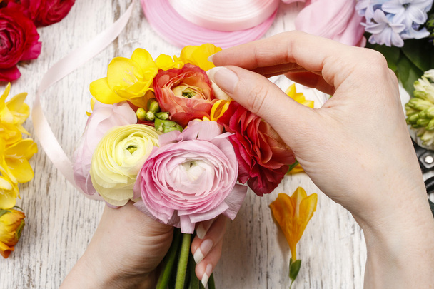 Nainen tekee kimpun persian leinikki kukkia
  - Valokuva, kuva
