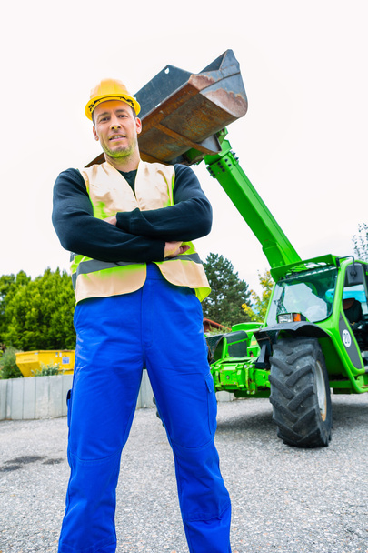 Builder in front of construction machinery - Foto, afbeelding