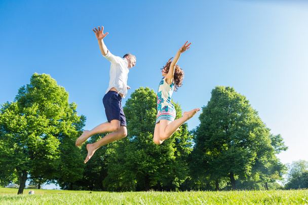 Couple amoureux sautant sur la pelouse du parc
 - Photo, image