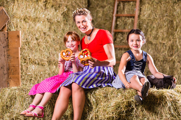 Bavarian family sitting on hayloft with pretzels - Photo, image