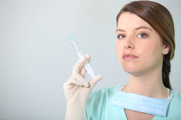 Brunette nurse holding syringe - Фото, изображение