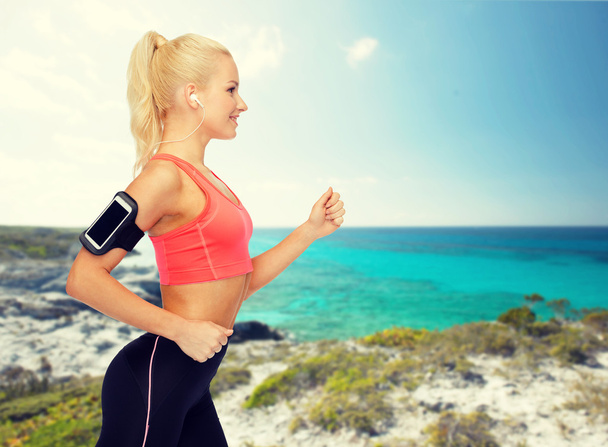 sporty woman running with smartphone and earphones - Photo, Image