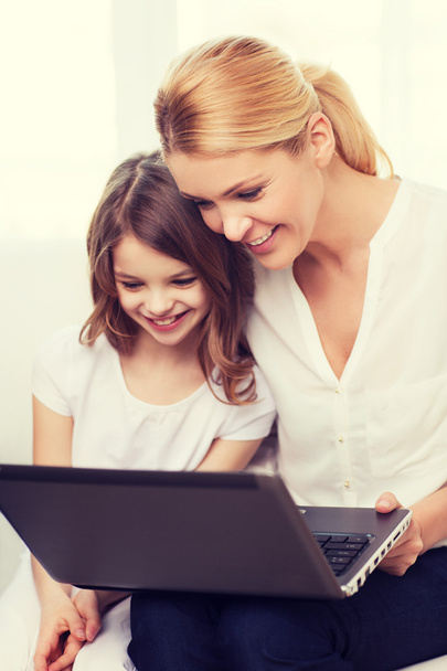 smiling mother and little girl with laptop at home - Foto, Bild