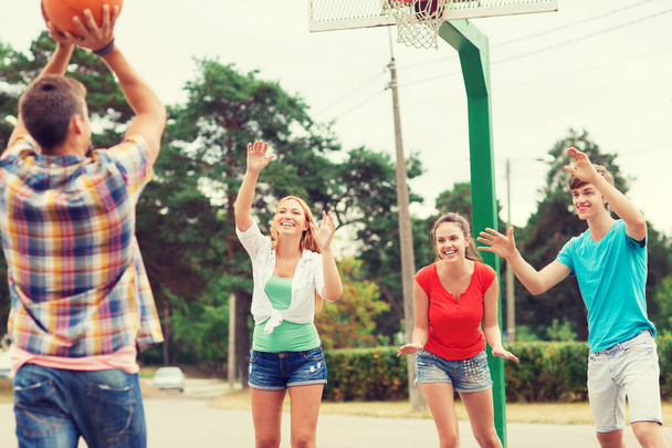 group of smiling teenagers playing basketball - Foto, afbeelding