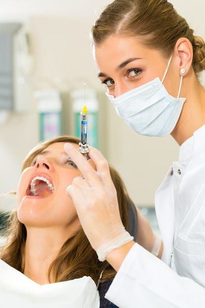 Dentiste tenant une seringue et anesthésiant sa patiente - Photo, image