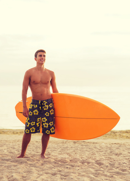 smiling young man with surfboard on beach - Photo, Image