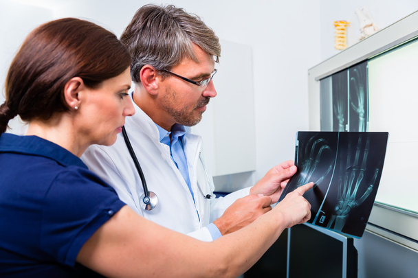 Médico com imagem de raio-X da mão do paciente
 - Foto, Imagem
