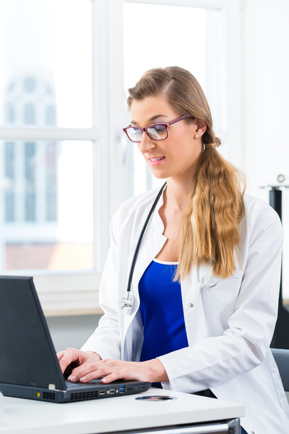 Female doctor writing on Pc in her clinic - Photo, Image