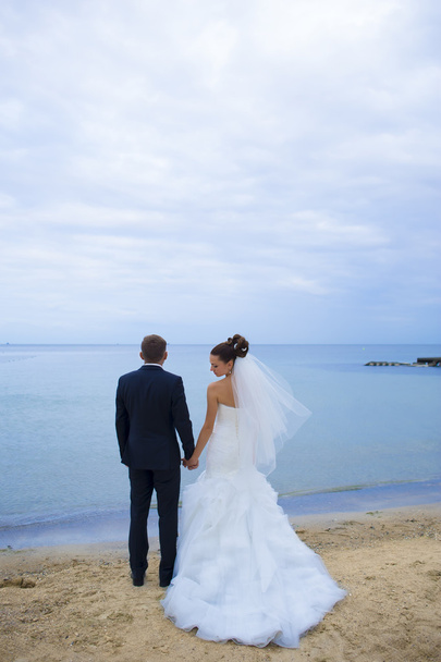 Nowożeńcy stoją na plaży. - Zdjęcie, obraz