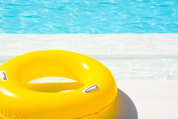 Flotador amarillo de la piscina en la piscina azul
 - Foto, imagen