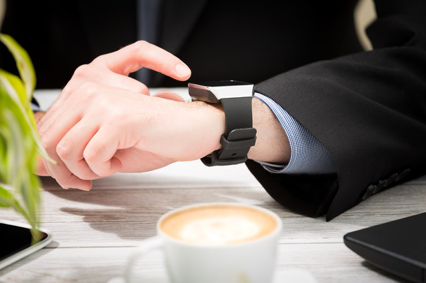 Businessman uses smart watch and phone. - Foto, Imagen