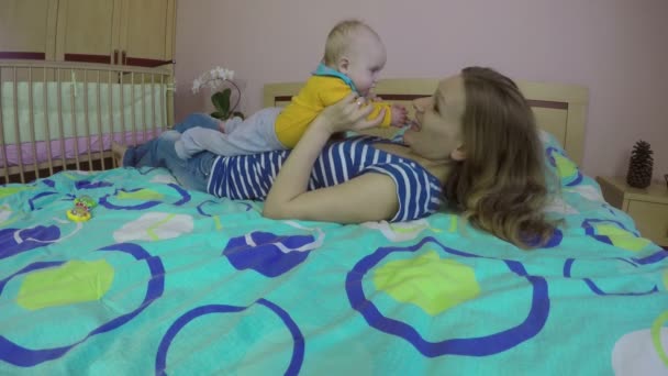 Liefhebbende vrouw en 5 maand oude babymeisje lachen en spelen op bed. 4k - Video