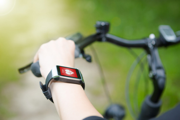 Femme en vélo avec un moniteur de fréquence cardiaque smartwatch
. - Photo, image