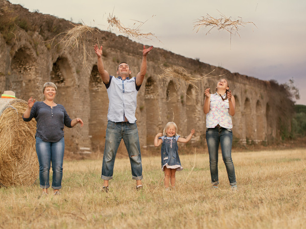Amusement de famille heureux sur le terrain avec des meules de foin
 - Photo, image