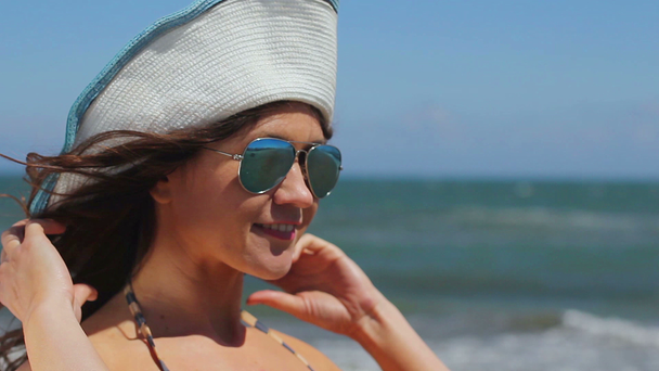 Professional female model posing for photo shoot on sea beach, smiling at camera - Felvétel, videó