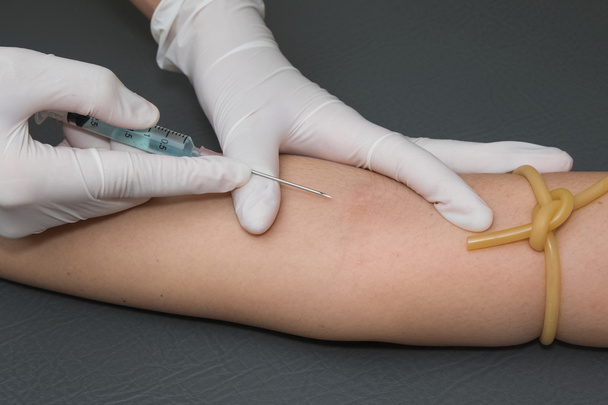 braço da mulher com um torniquete recebendo injeção com uma seringa em
  - Foto, Imagem