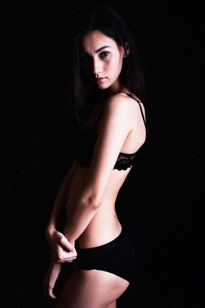 lowkey portrait of beautiful woman in black underwear over dark  - Photo, Image