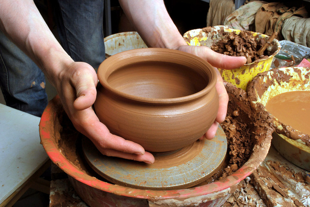 Handen van een pottenbakker, het creëren van een aarden pot op de cirkel - Foto, afbeelding