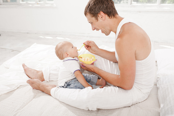 Young father with his nine months old son on the bed at home - Foto, Imagem