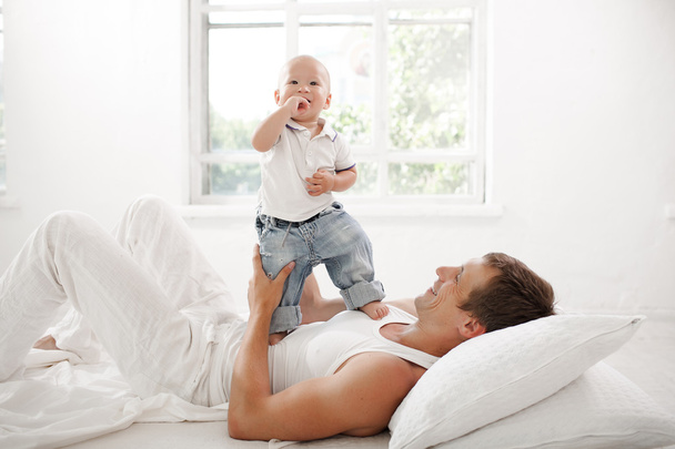 young father with his nine months old son on the bed at home - Foto, afbeelding