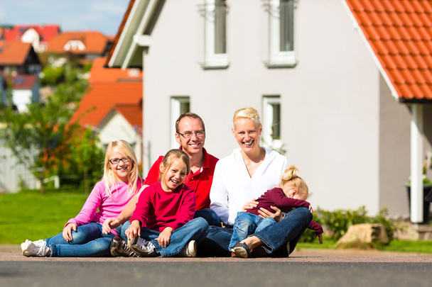 Happy family sitting in front of home - Photo, Image