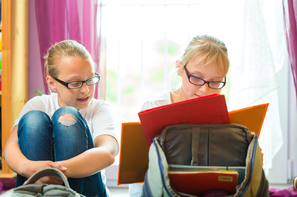 Girls doing homework and packing school bags - Photo, image