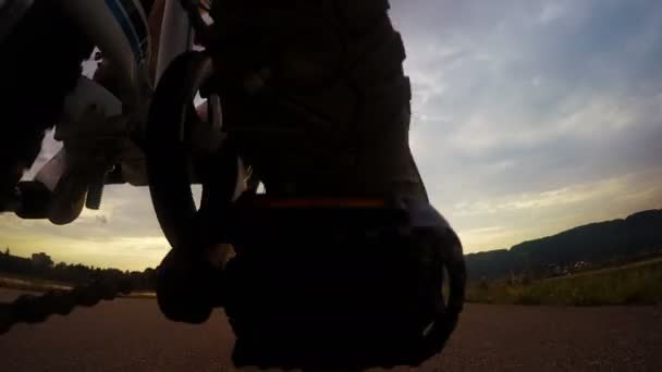Kleine jongen gaat op fiets voorwaartse zonsopgang door de asfaltweg - Video