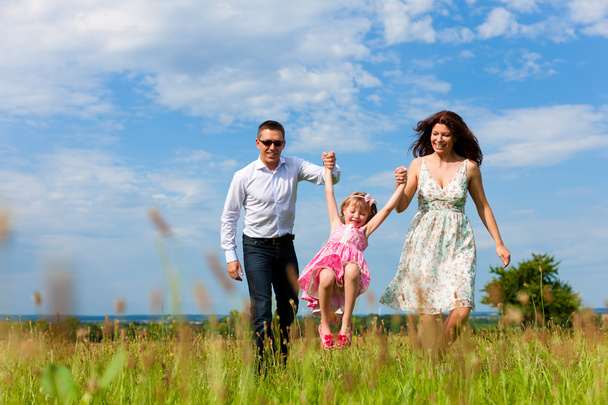 Familia feliz corriendo en el prado en verano
 - Foto, imagen