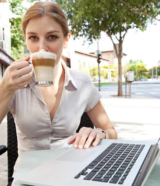 business woman drinking  a hot beverage coffee and using a laptop - Zdjęcie, obraz
