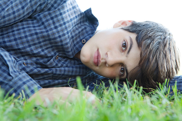 boy laying down on green grass in a park - Zdjęcie, obraz