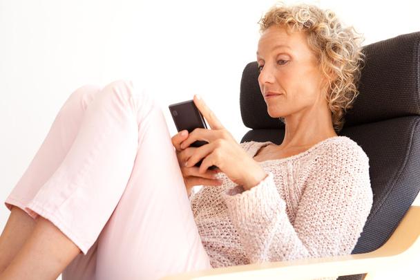 woman in an armchair using a smartphone - Zdjęcie, obraz