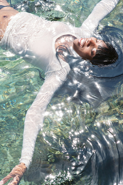 mujer negra nadando y flotando en un mar
 - Foto, imagen