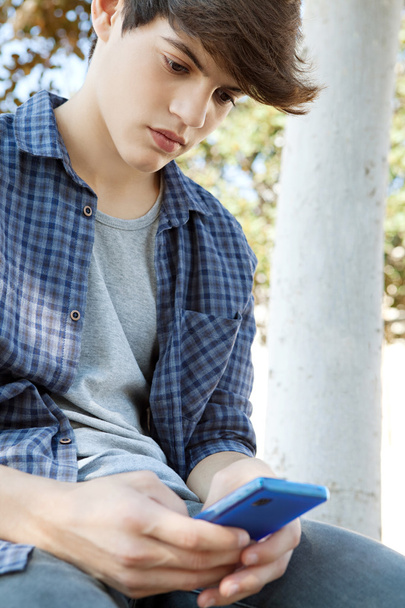 teini-ikäinen poika käyttää älypuhelimen mobiili
 - Valokuva, kuva