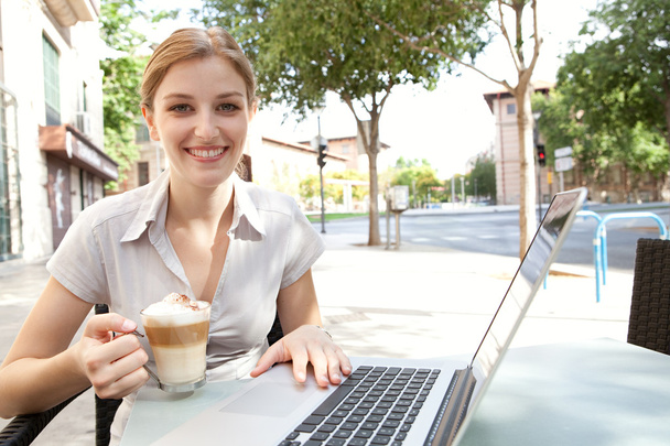 mulher de negócios bebendo um café e usando um computador portátil
 - Foto, Imagem
