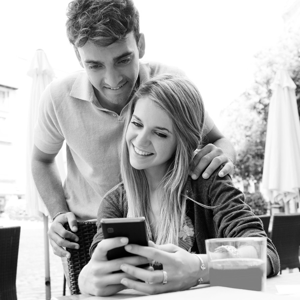 pareja usando un teléfono inteligente en la cafetería
 - Foto, imagen