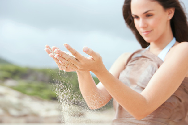 femme avec des grains de sable filtrant à travers ses mains
 - Photo, image