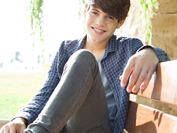 Junge sitzt auf einer Holzbank in einem Park - Foto, Bild