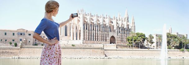 girl using a smartphone to take photos of a cathedral - Fotoğraf, Görsel