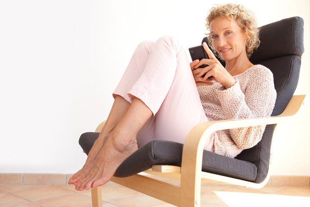 nainen nojatuolissa älypuhelimella
 - Valokuva, kuva
