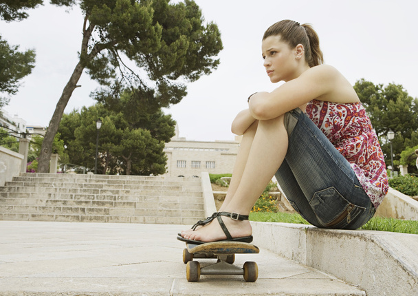 chica sentada con su patineta
 - Foto, imagen