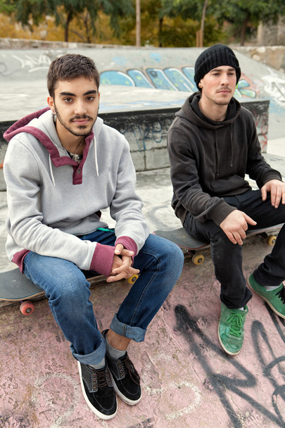 two teenagers friends sitting at a skateboarding park - Фото, изображение