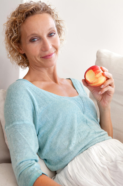 woman eating a apple on a couch at home - Fotografie, Obrázek