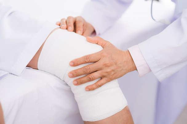 Ortopedista examinando joelho torcido
 - Foto, Imagem