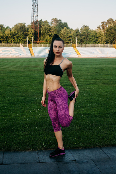 Slim athletic woman with dumbbells in the stadium - Foto, afbeelding