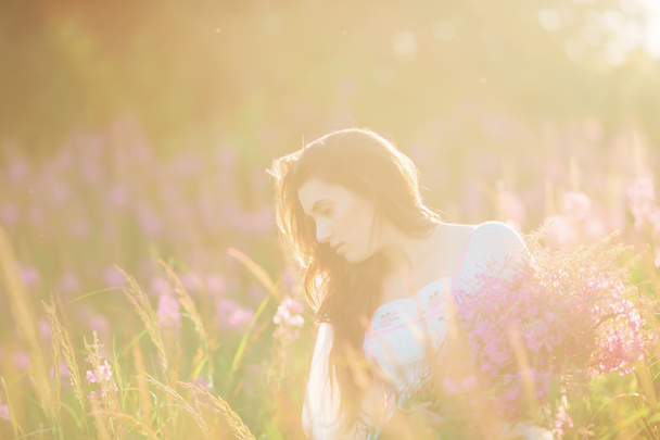 Красива молода дівчина, що тримає лаванду в полі на заході сонця. ходити
 - Фото, зображення