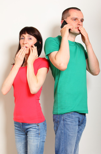 Shocked woman and man talking on mobile phone - Fotó, kép