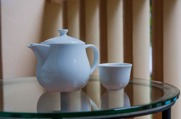 Tetera y taza de té en una mesa de cristal en la terraza
. - Foto, Imagen
