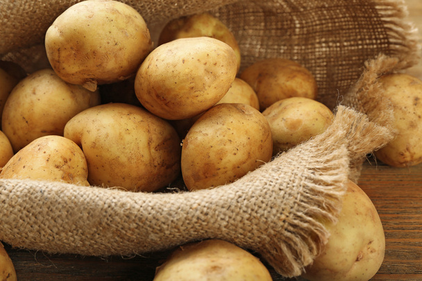 Young potatoes on sackcloth close up - Foto, afbeelding