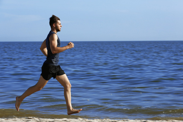 Young man jogging on beach - Фото, изображение