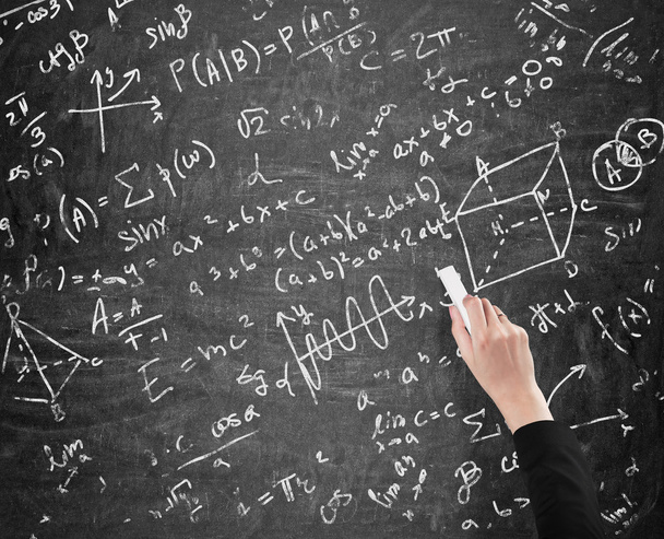 A woman's hand is writing math calculations on black chalk board. Analyst. - Foto, Imagen